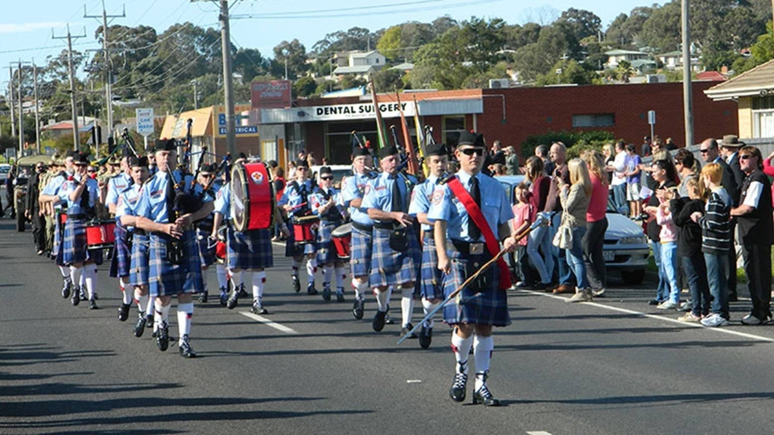 Band members playing on their instruments as they march down the street.
