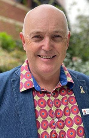 A man in a colourful short smiles at the camera