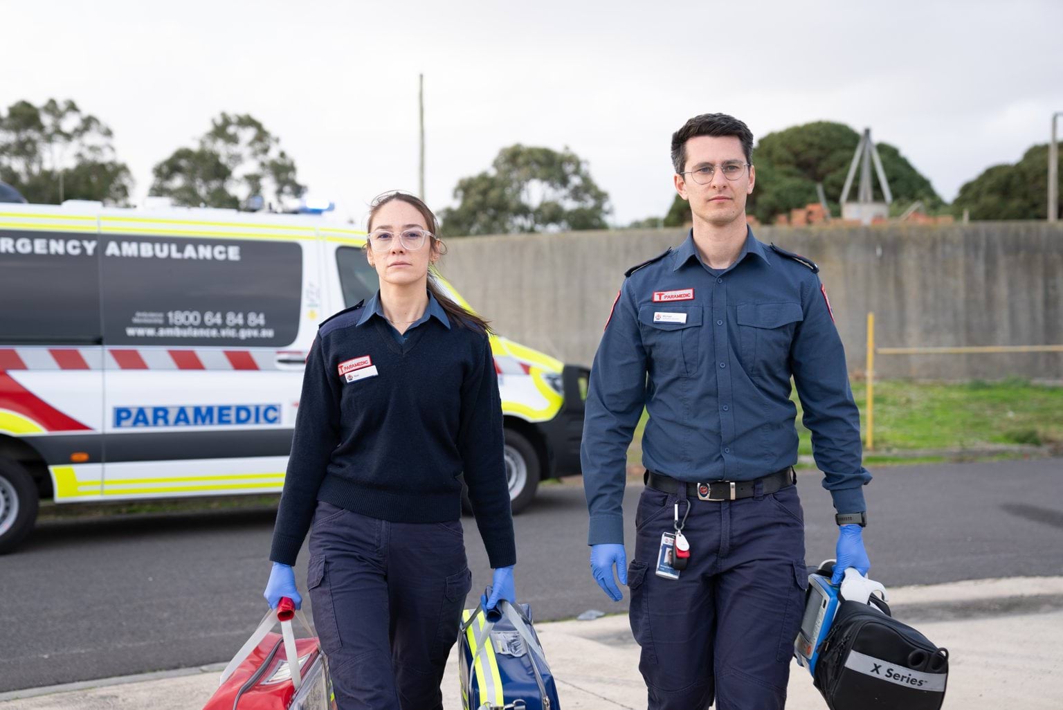 Two paramedics holding bags and walking towards the camera.