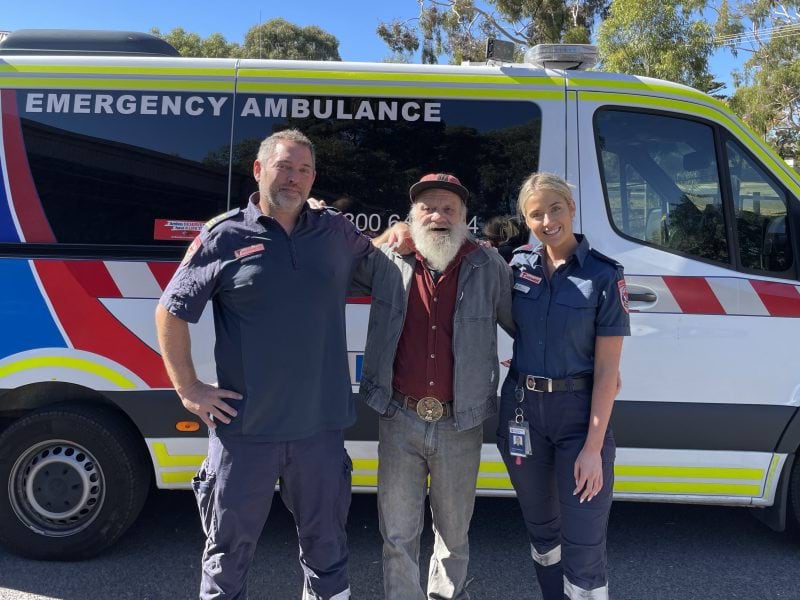 Photograph showing Ian Blacket stading with two paramedics in front of an ambulance