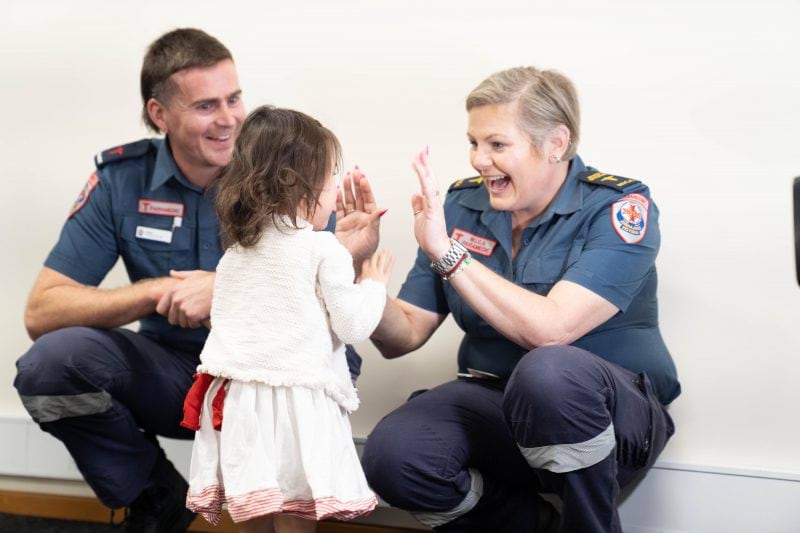 A woman paramedic high fives a little girl.