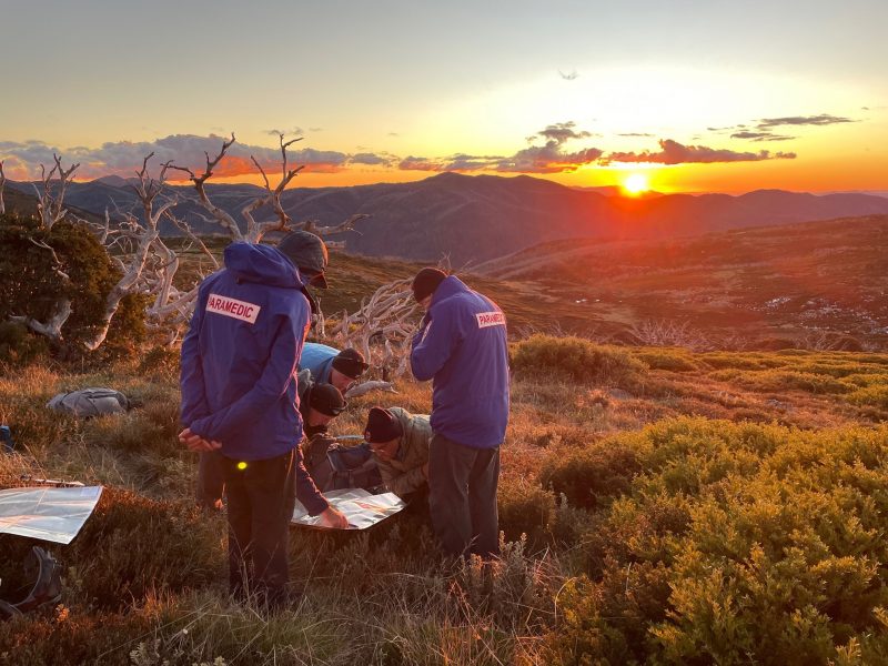 A group of people looking at a map with a sunset in the background.