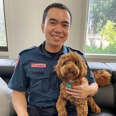 A male paramedic smiling and hugging while seated on a couch.