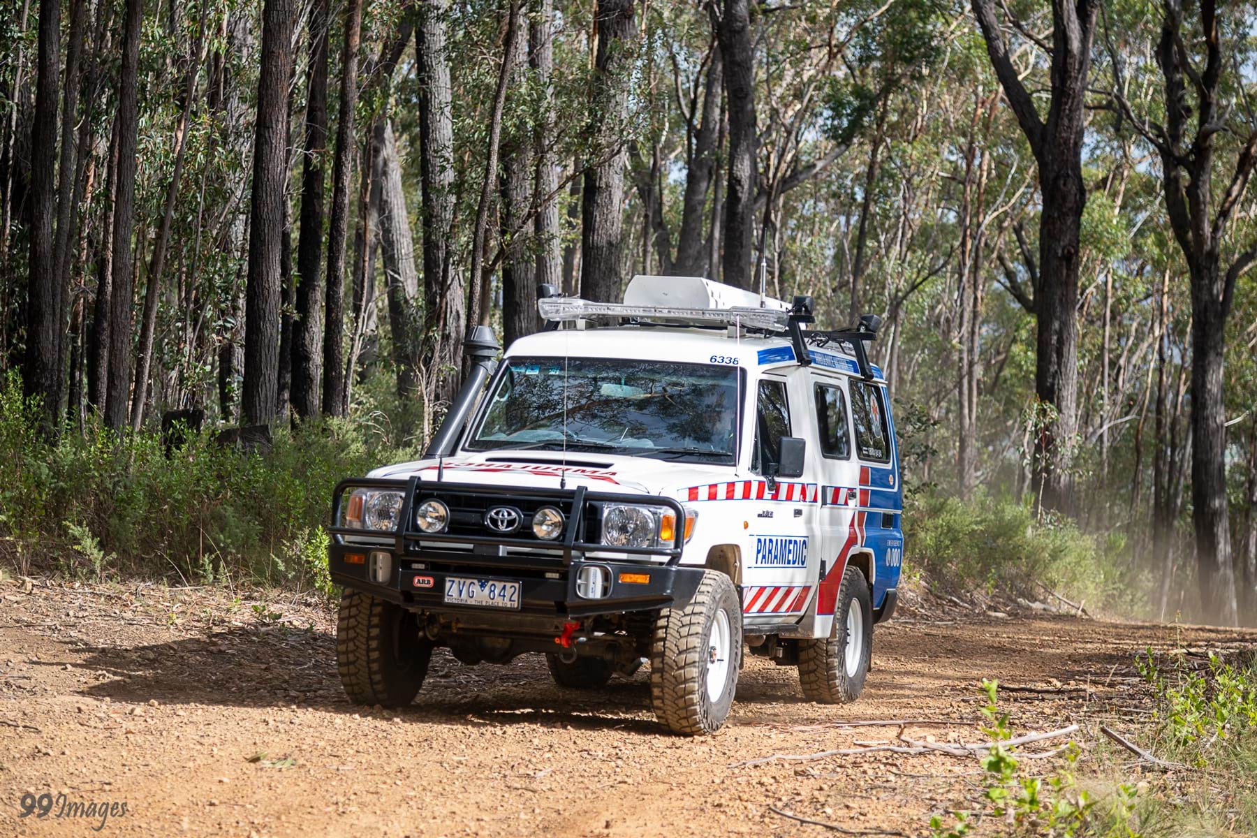 A four-wheel drive ambulance drives along a dirt track in the bush