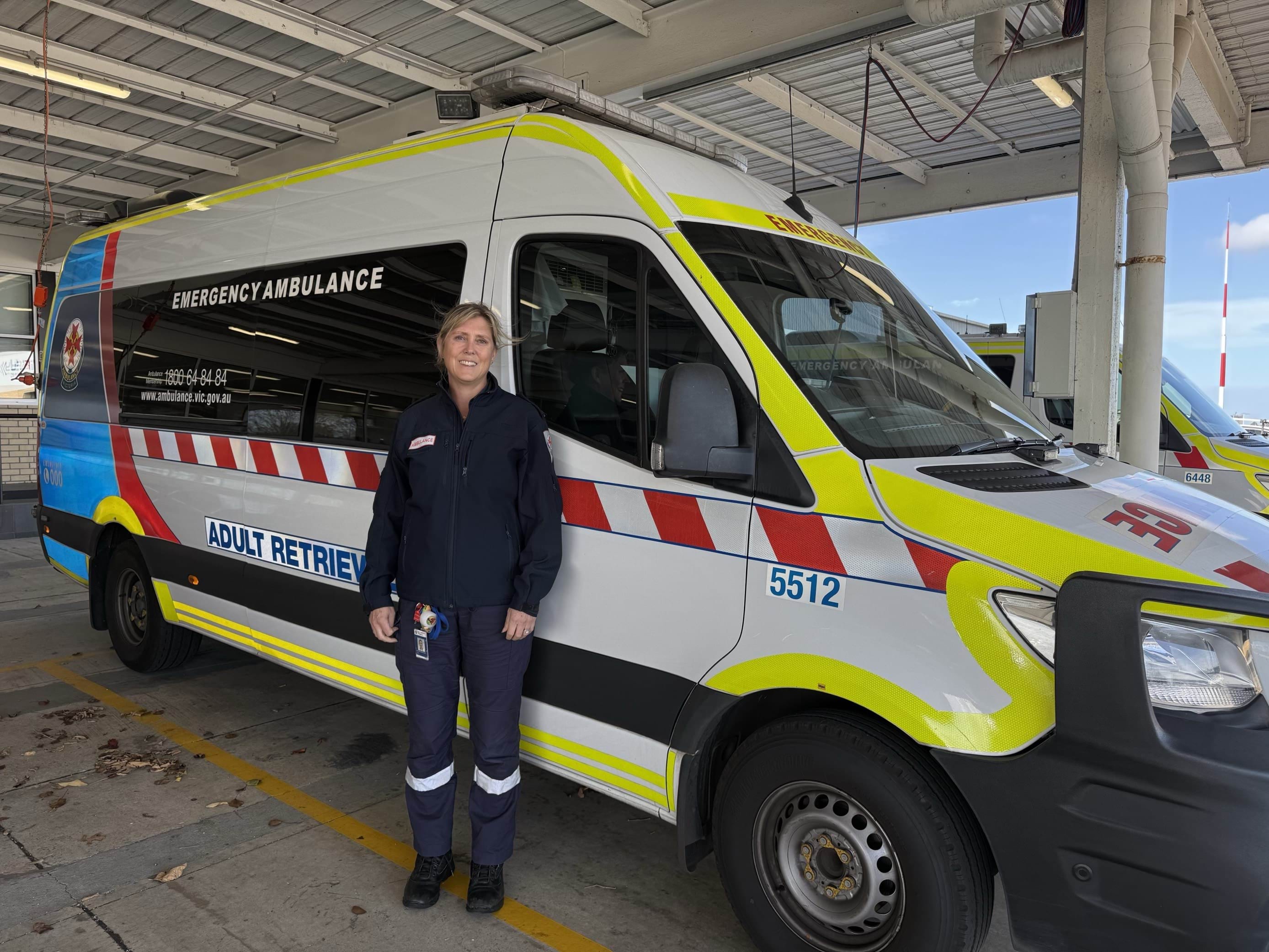 A woman stands in front of an Adult Retrieval Victoria ambulance.