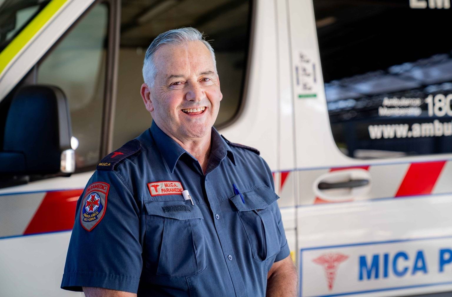 A smiling man in front of an ambulance.