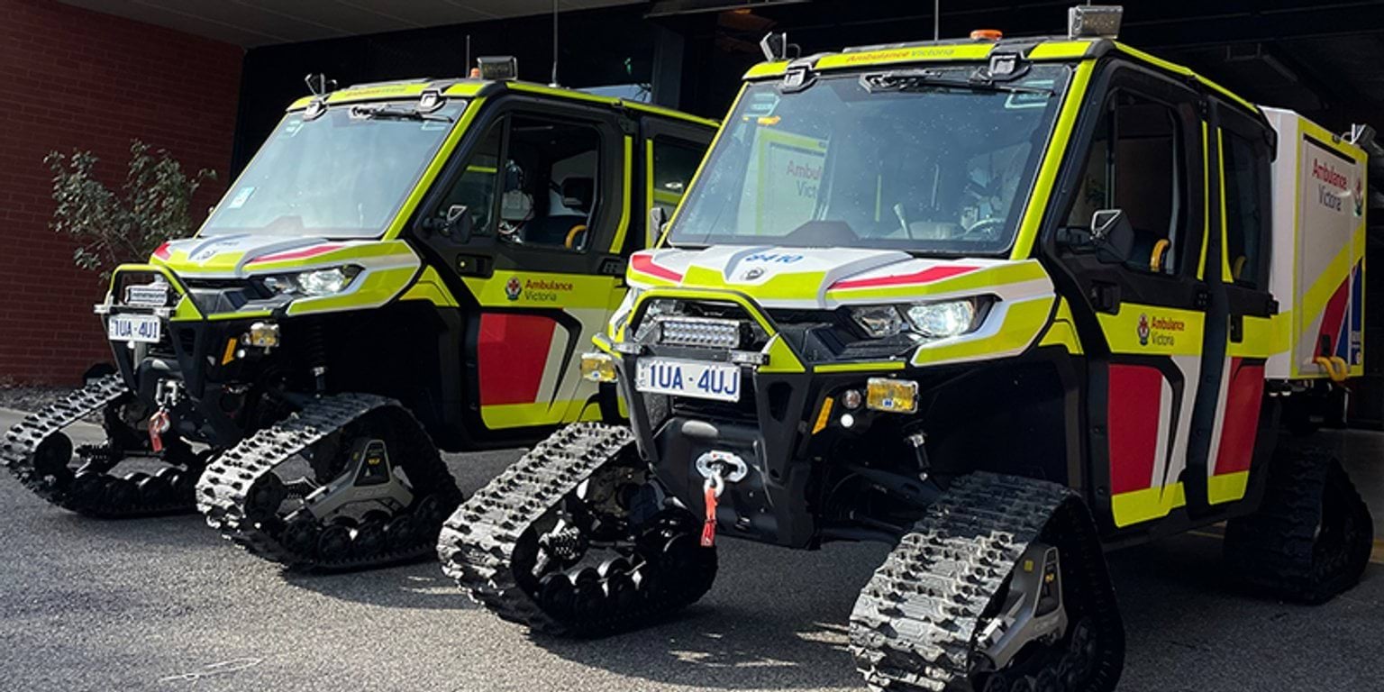 Two yellow and black emergency snow vehicles parked in front of a building.