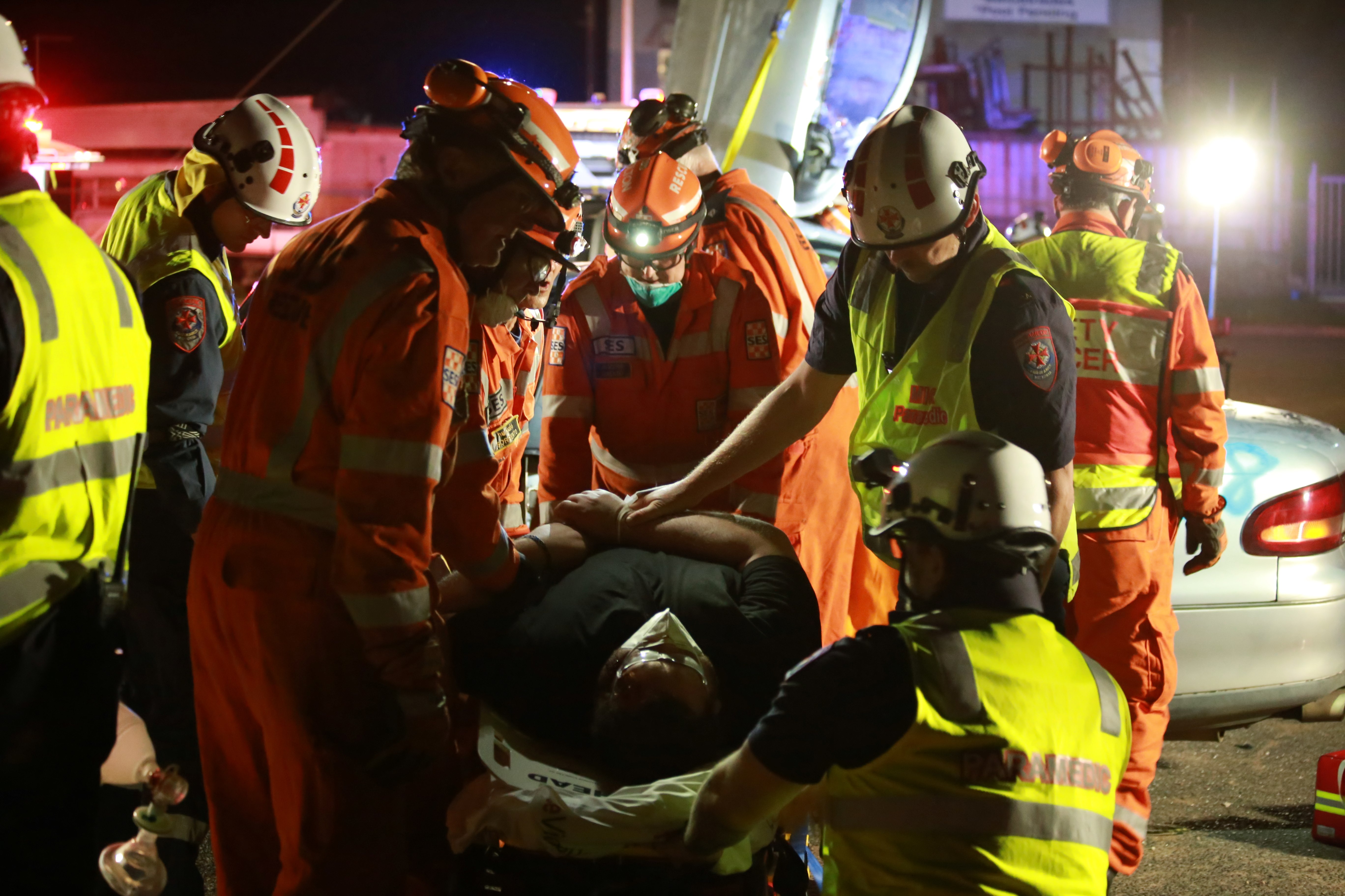 Paramedics and SES volunteers surround a patient on a stretcher.