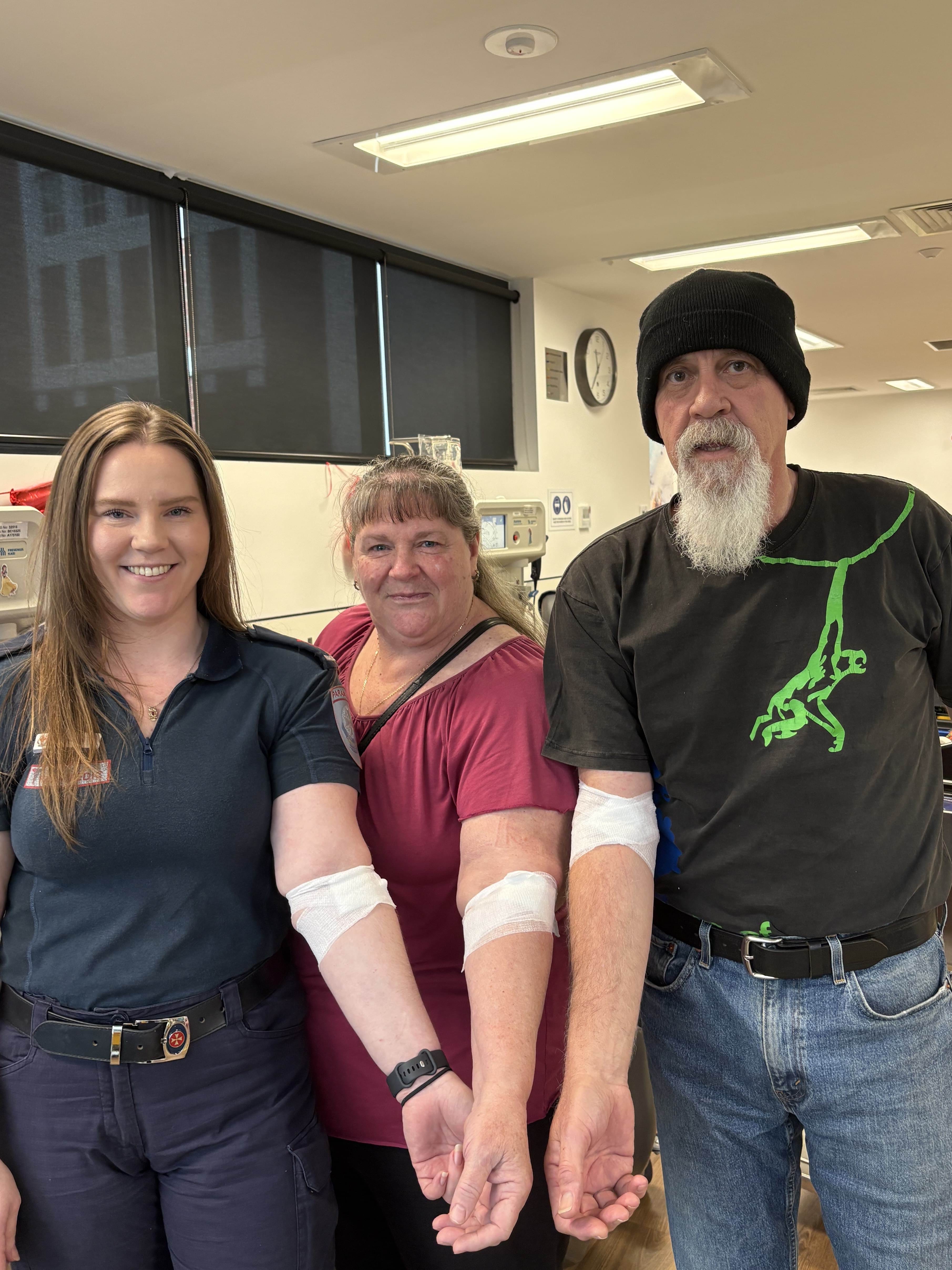 Three people holding their arms out to the camera to show the bandage where they donated blood. 
