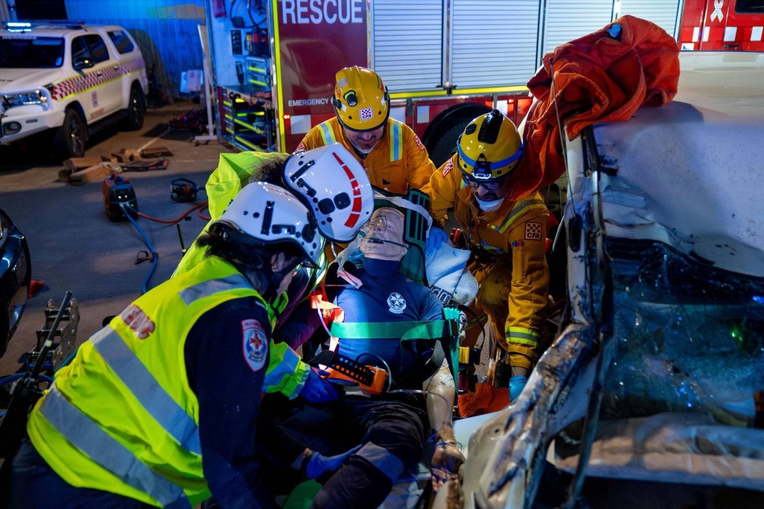Paramedics and CFA members lift a mannequin out of a crashed car.