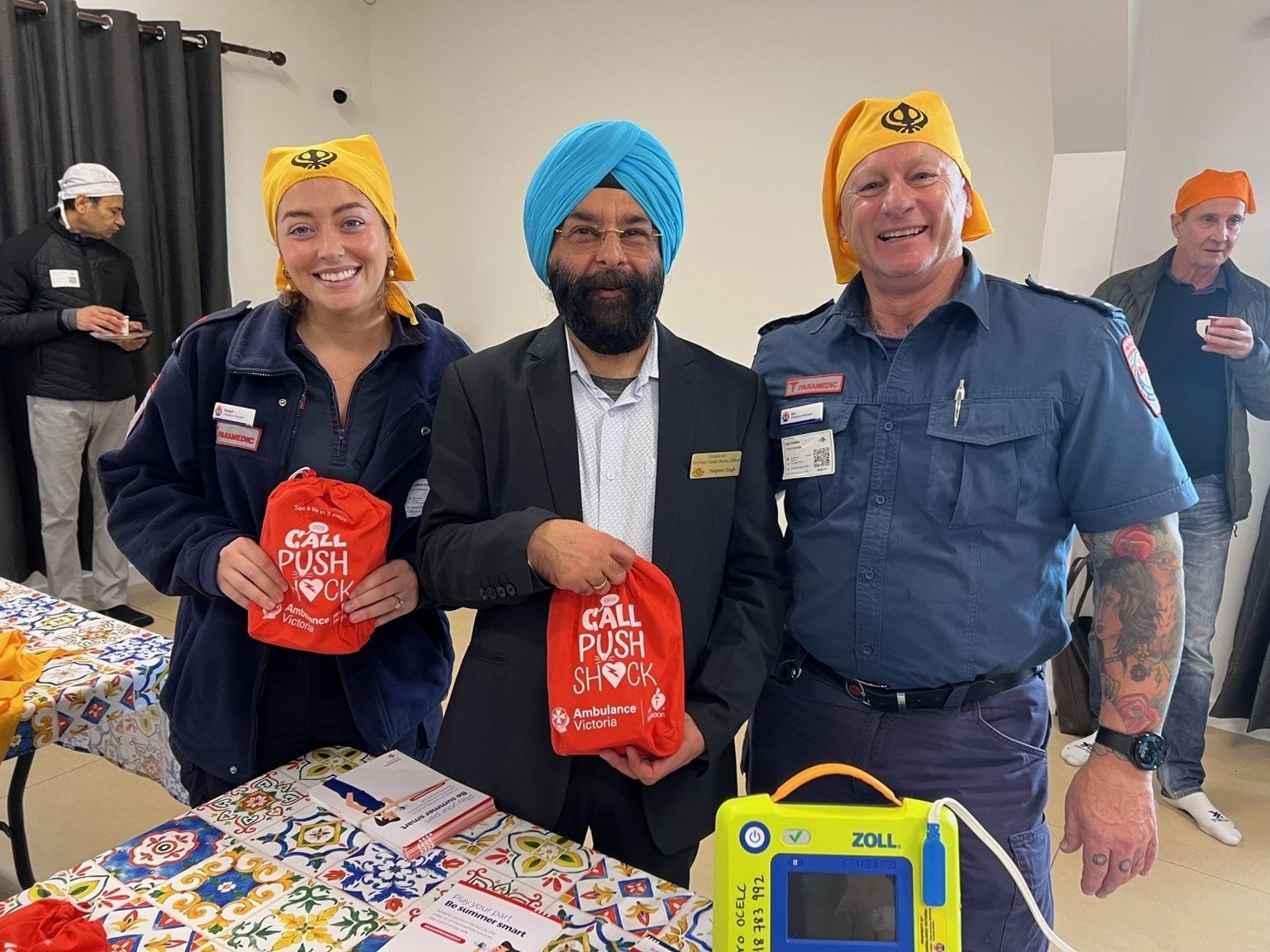 Two smiling paramedics standing either side of a man.