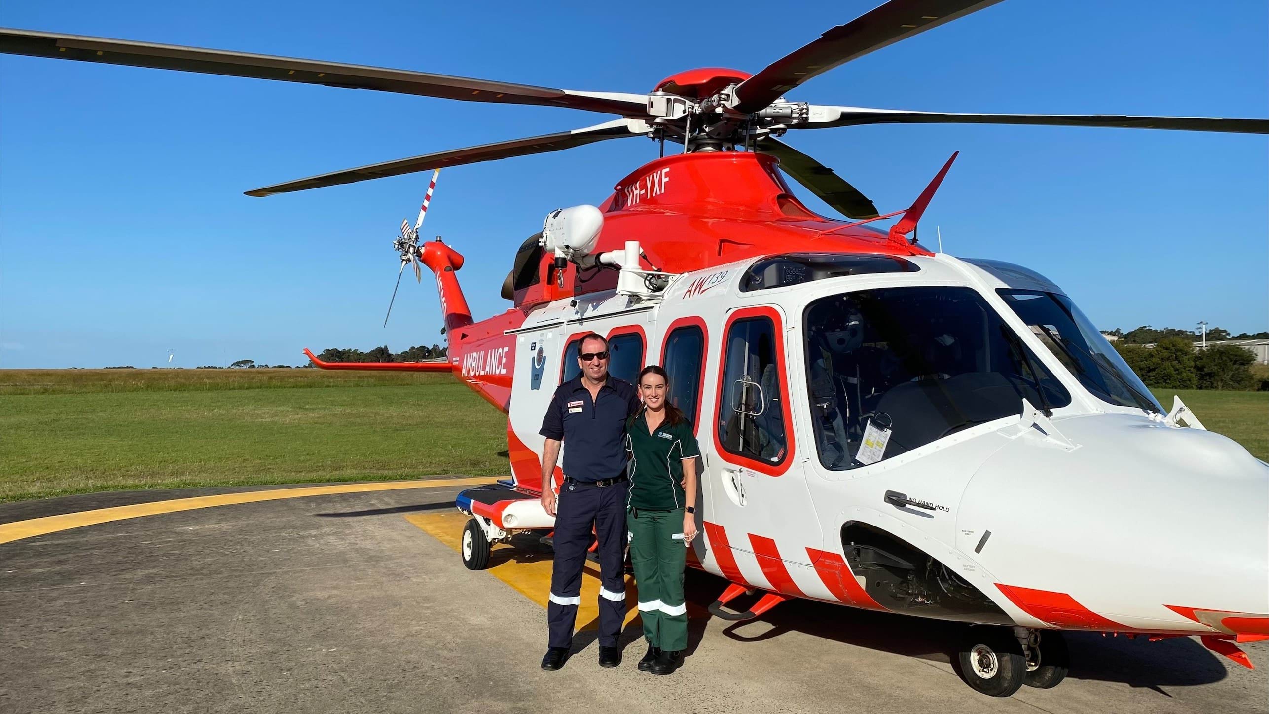 A man and woman standing in front of a helicopter.
