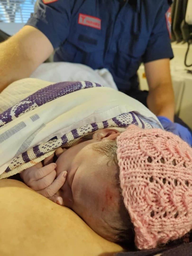 A newborn baby. A paramedic's uniform is in the background.