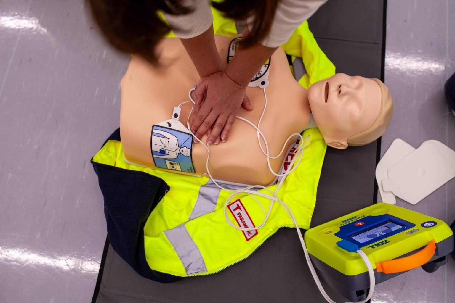 Photo of someone practicing CPR and using an AED on a mannequin.