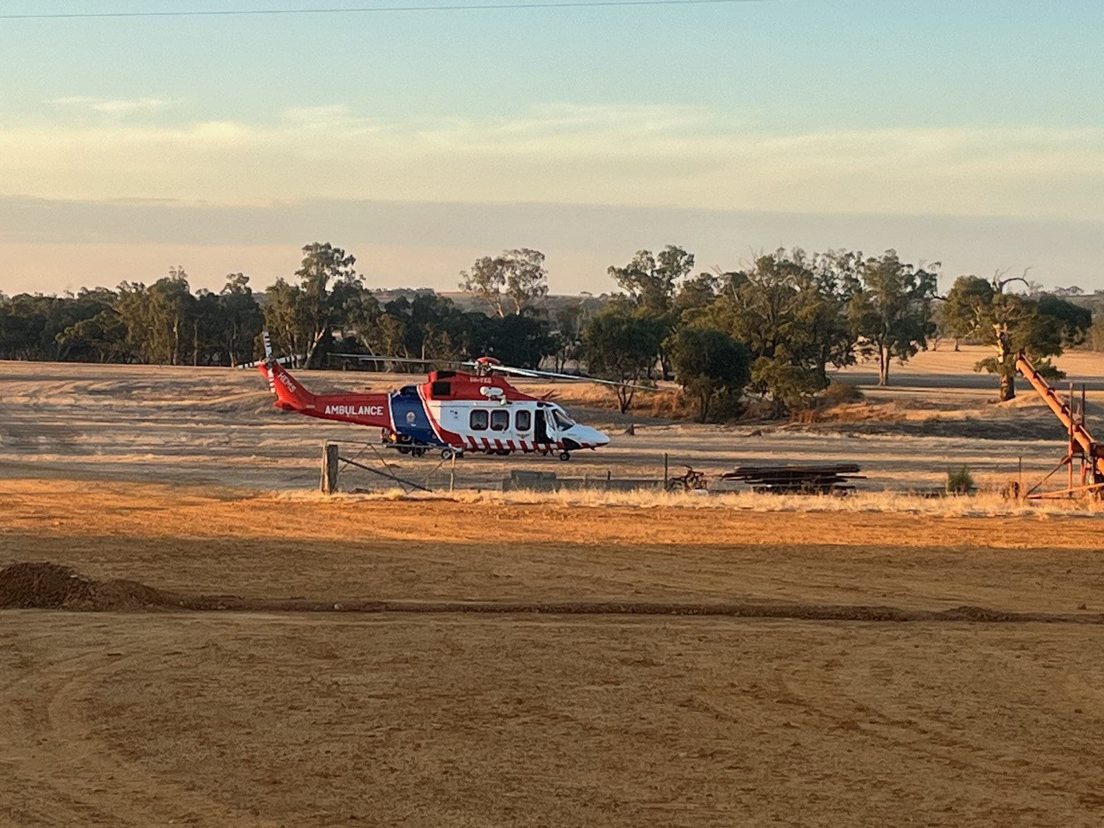 An Air Ambulance Victoria helicopter on farmland.