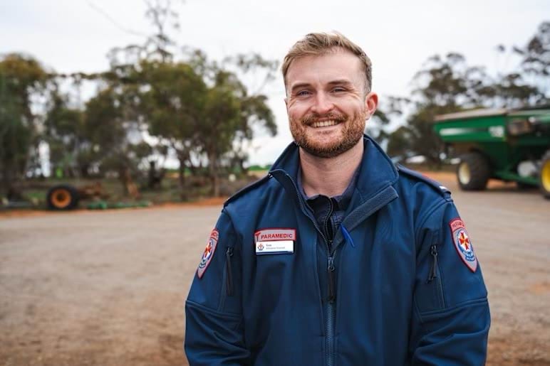A paramedic smiles for the camera on a farm.