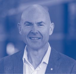 A man in business clothes looks directly at the camera