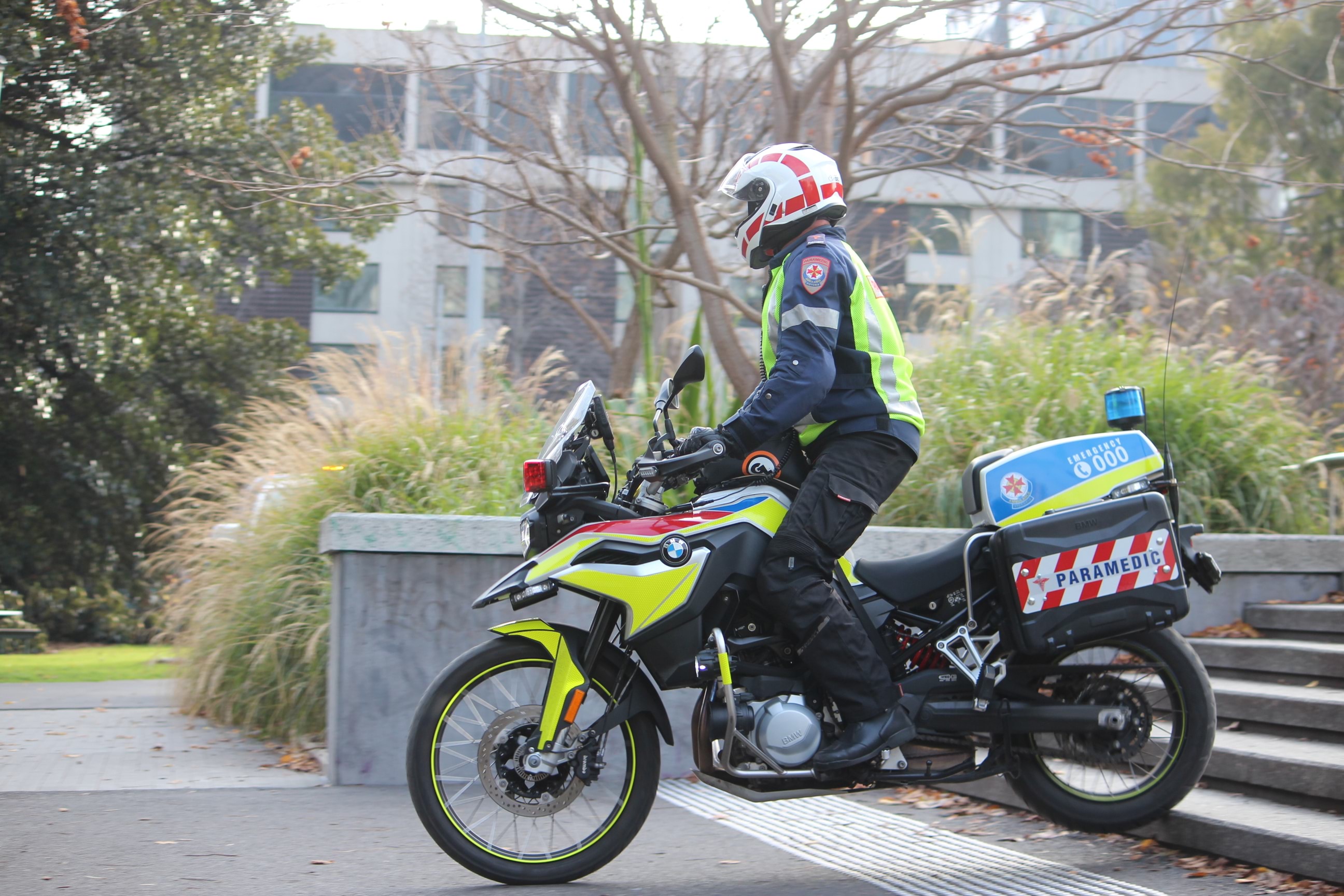 A motorcycle paramedic riding down stairs in a park.