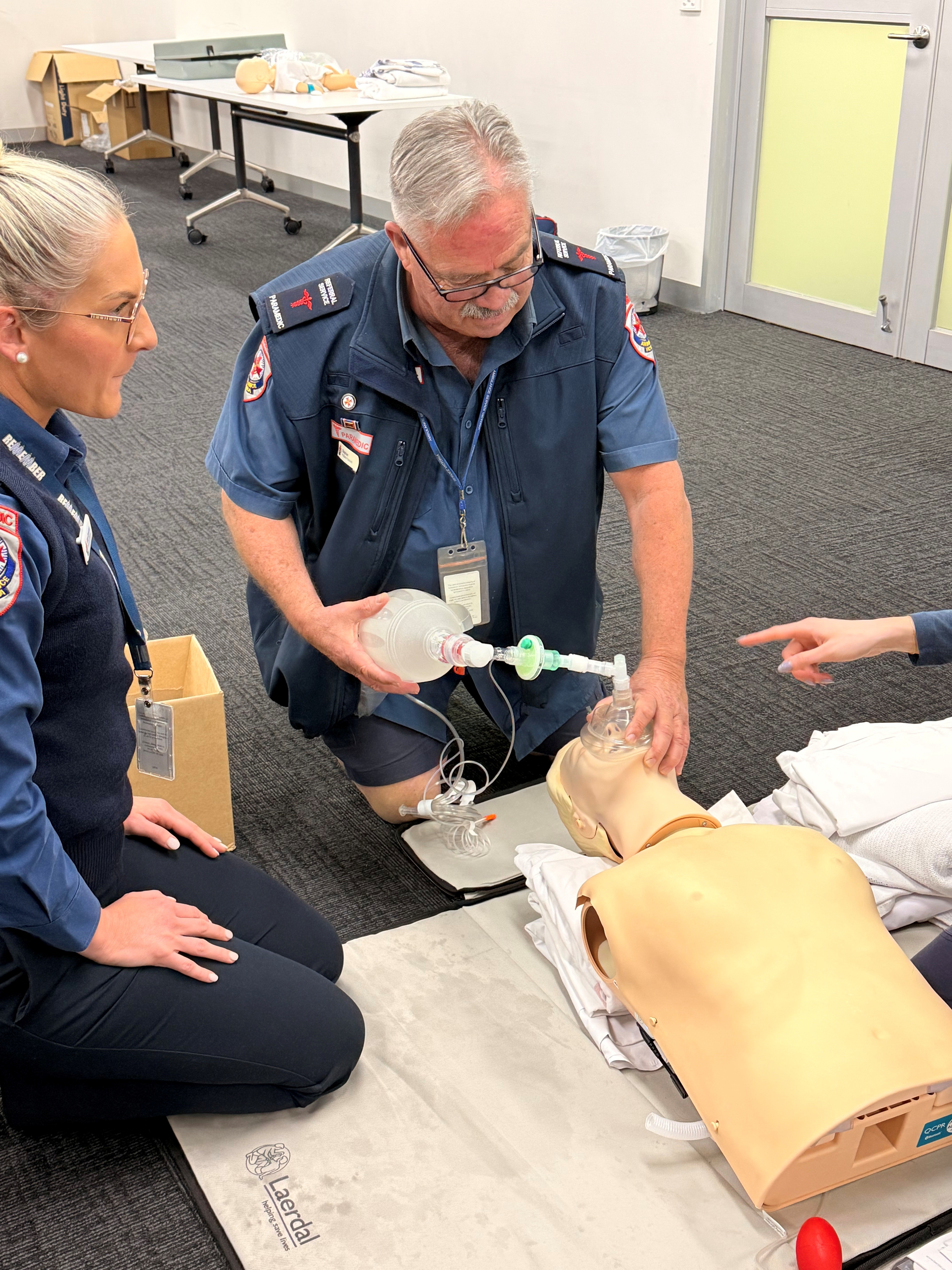 A male paramedic practicing ventilation on a manikin.