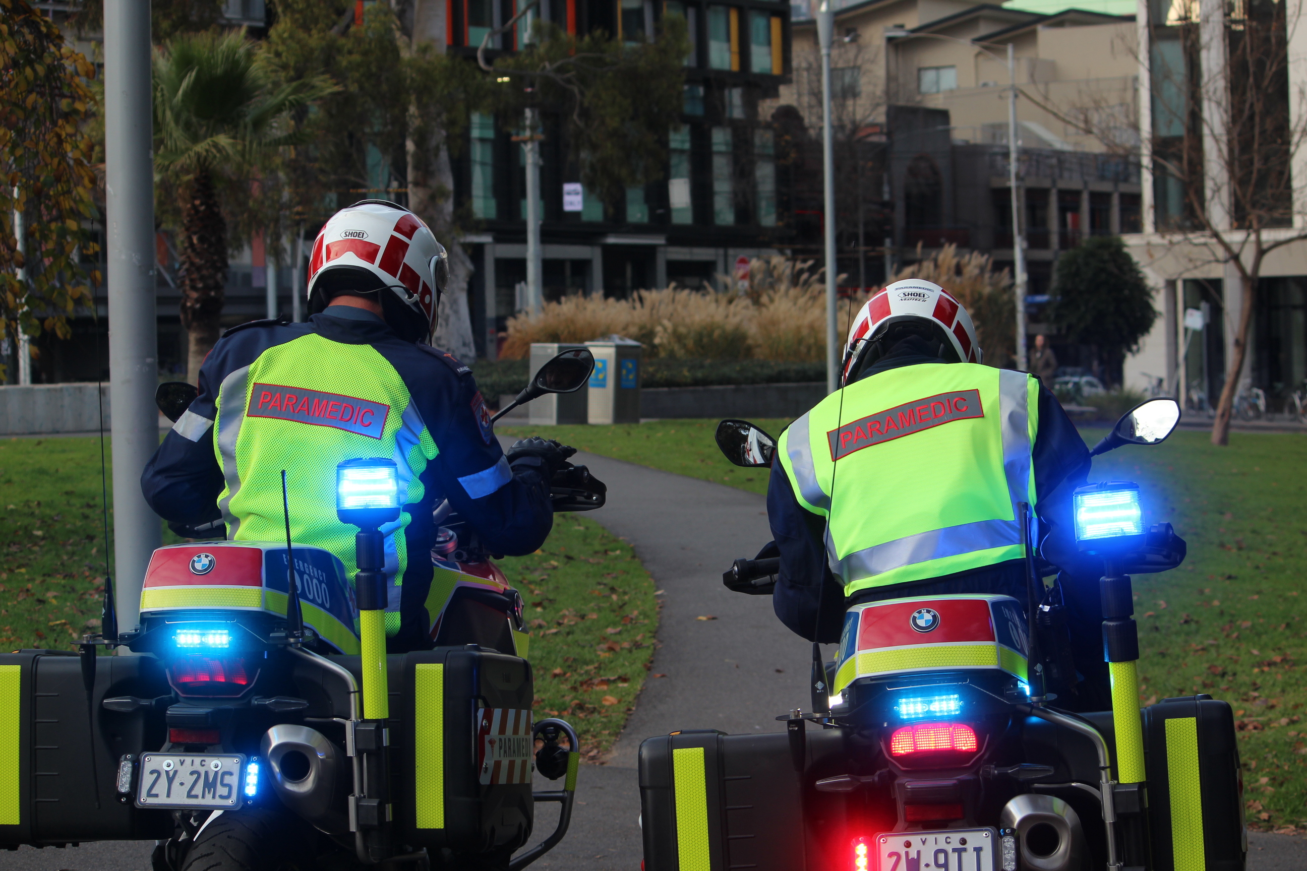 Two motorcycle paramedics riding through a park.