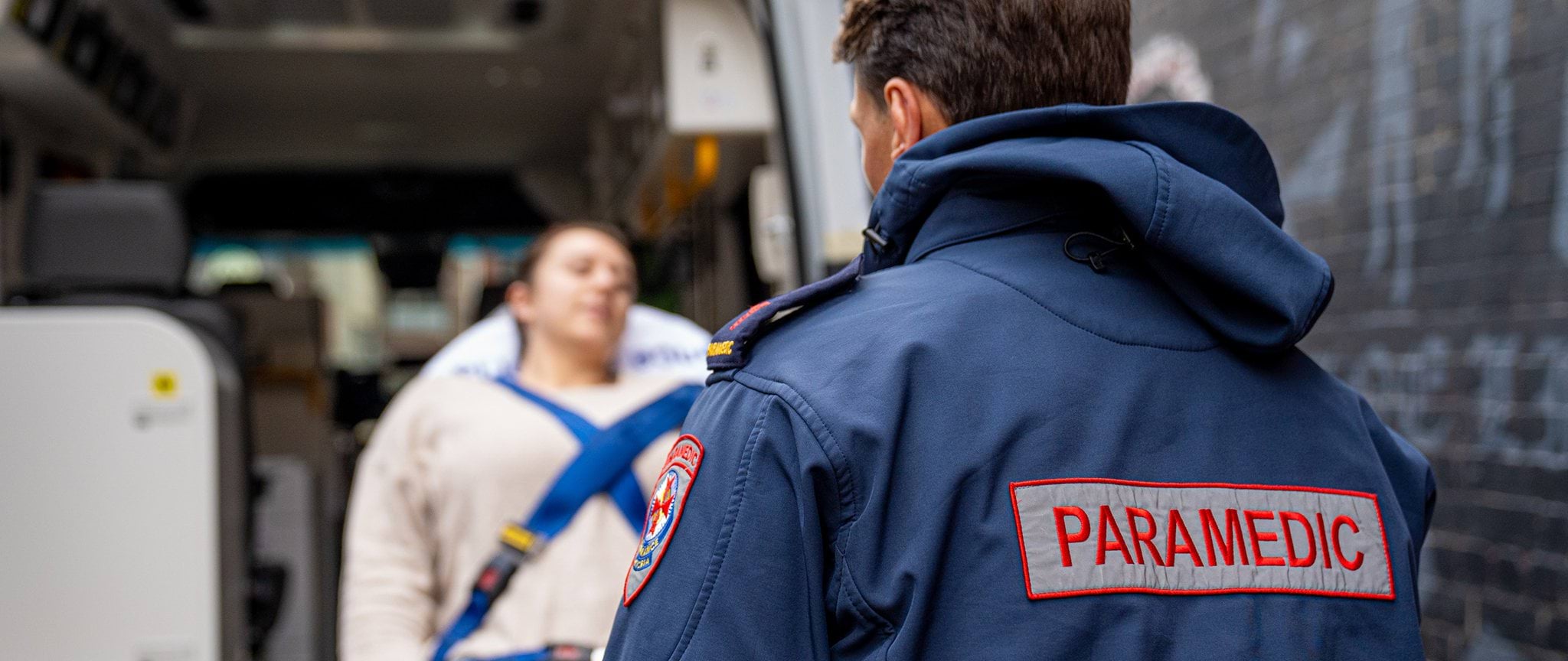 image shows a paramedic from behind as he loads a patient into an ambulance