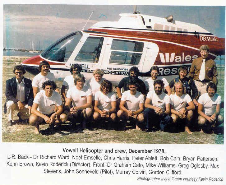 A group photo of people in front of a rescue helicopter.