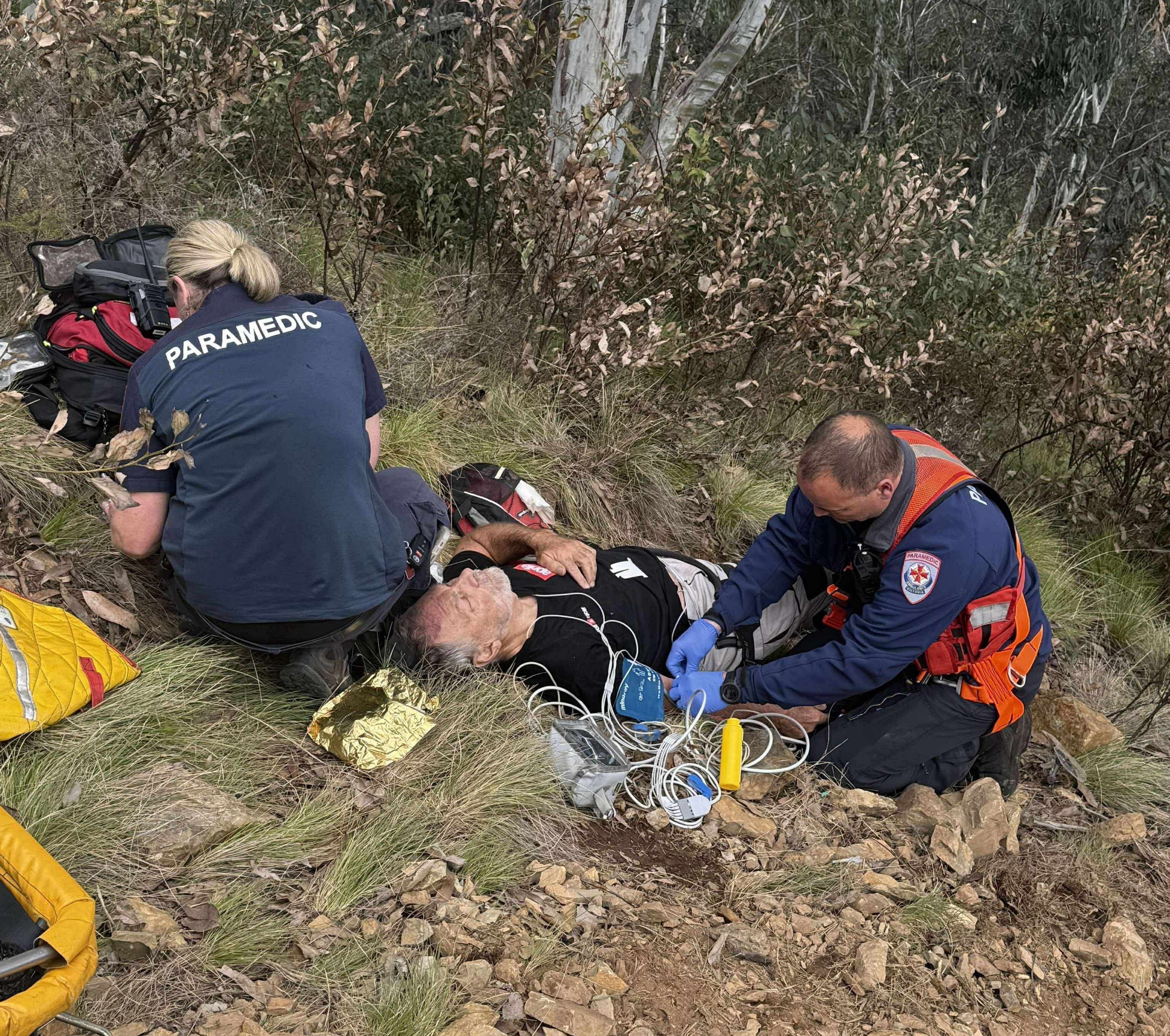 A female and male paramedic treating a man lying on the ground. 