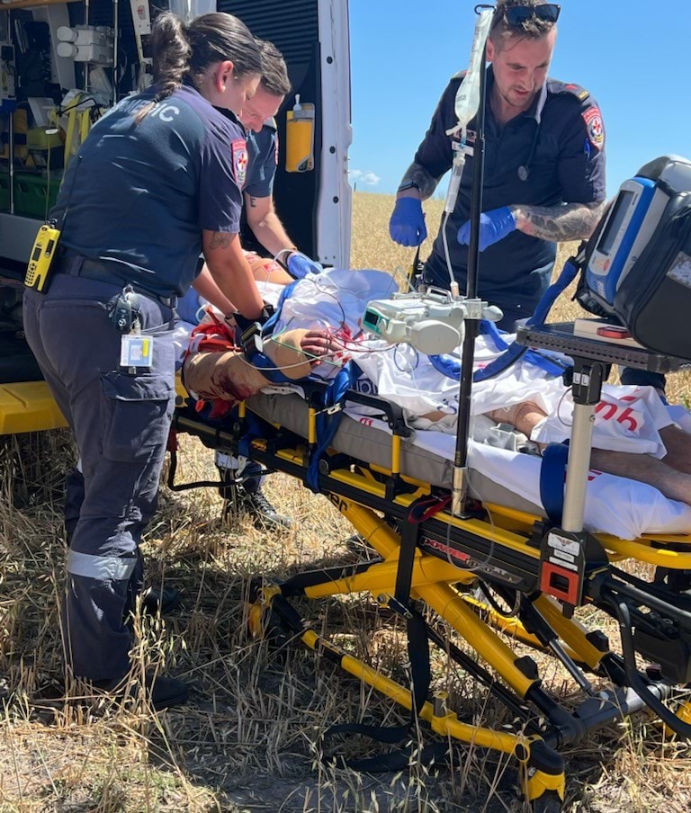 One person on a stretcher being attended to by three paramedics.