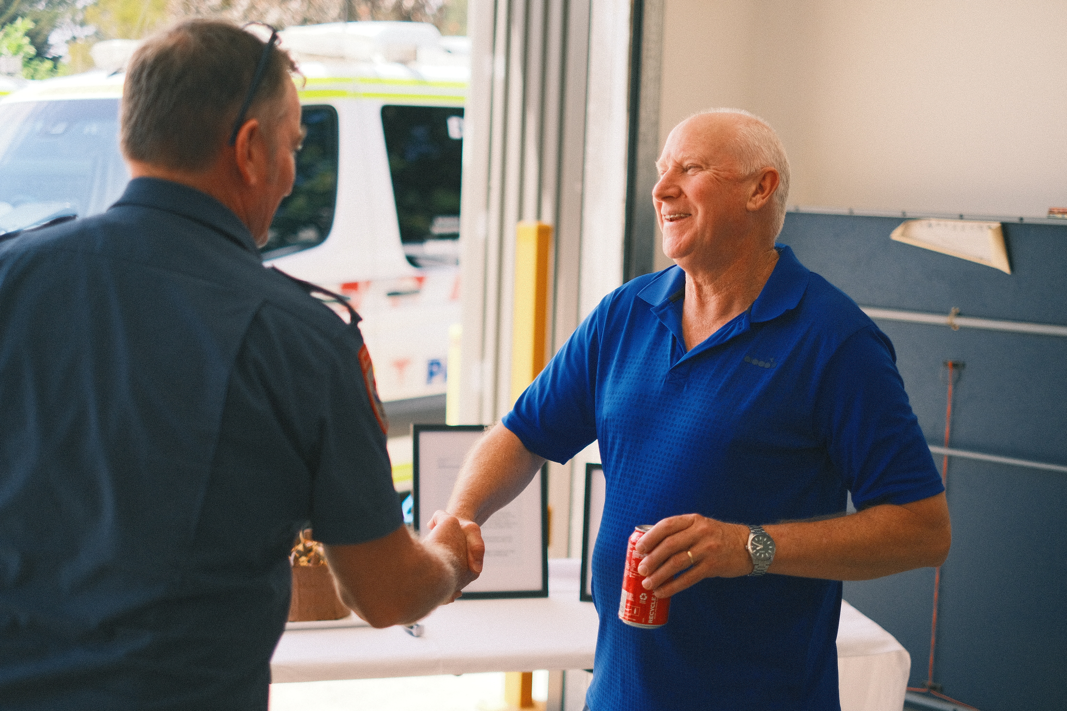 A man shakes hands with someone in Ambulance Victoria uniform.