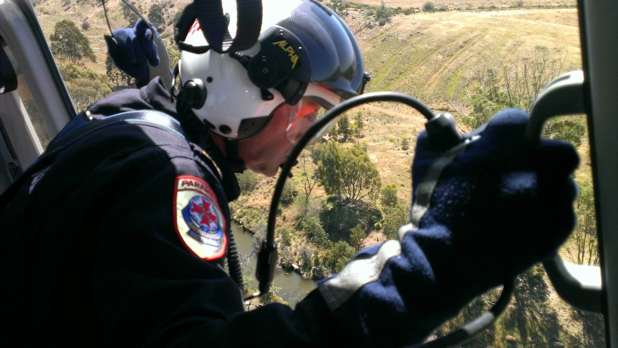 A MICA Flight Paramedic looking out the door of a flying HEMS air ambulance.