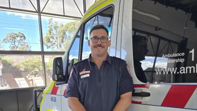 A man wearing a paramedic uniform standing in front of an ambulance.
