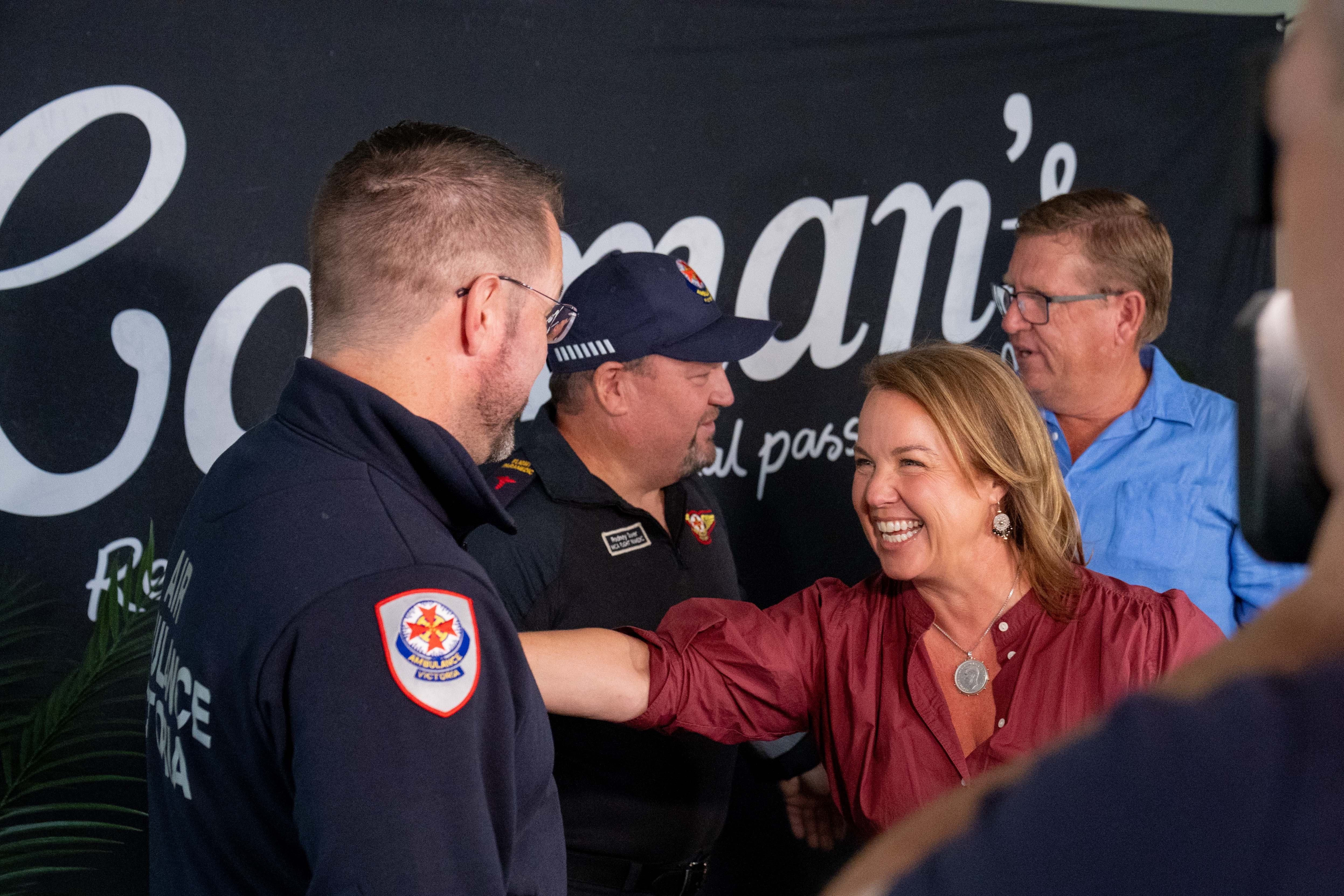A woman and man speak with two people wearing Air Ambulance Victoria uniform.