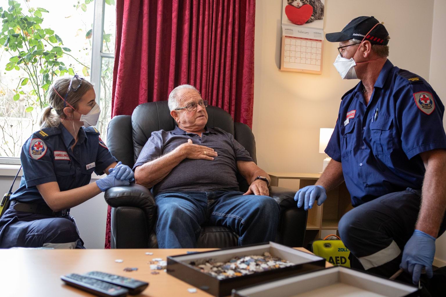 Paramedics attend to a man in his home.