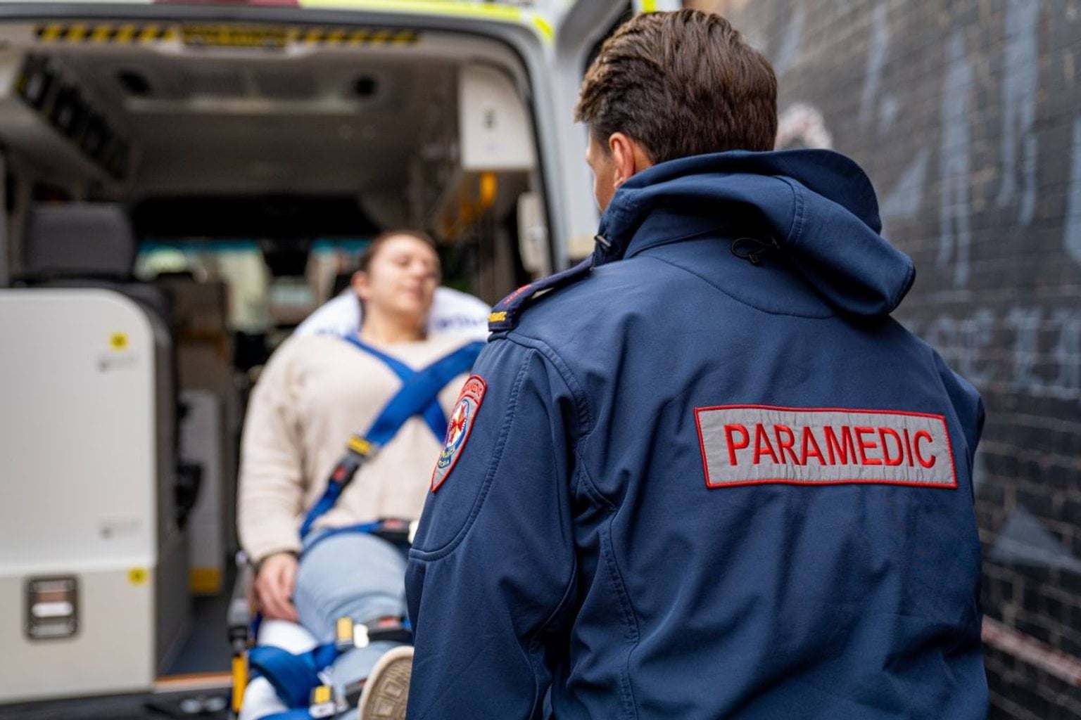 A paramedic loads a patient on a steatcher into an ambulance