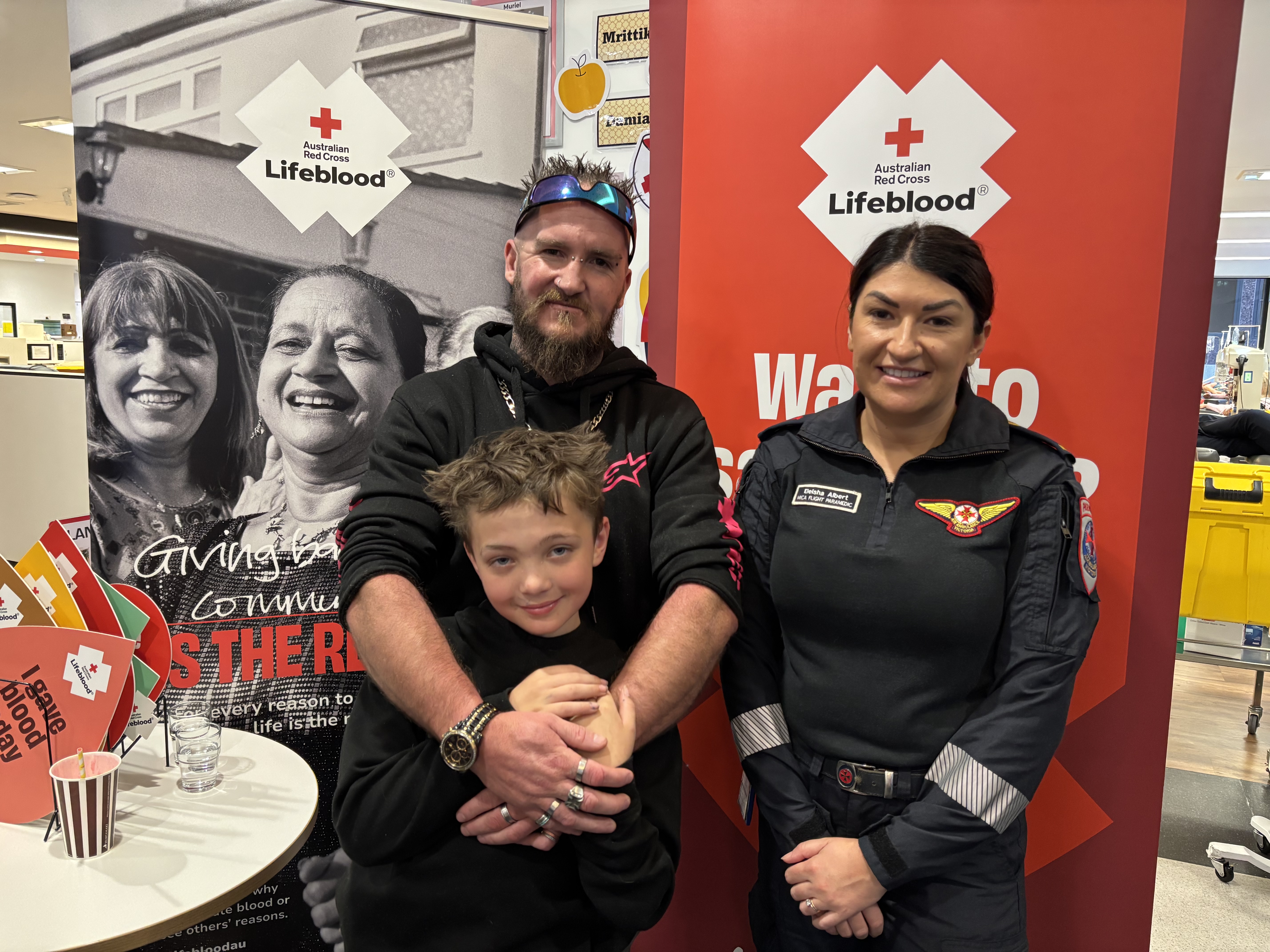 A paramedic is standing with a patient and his son