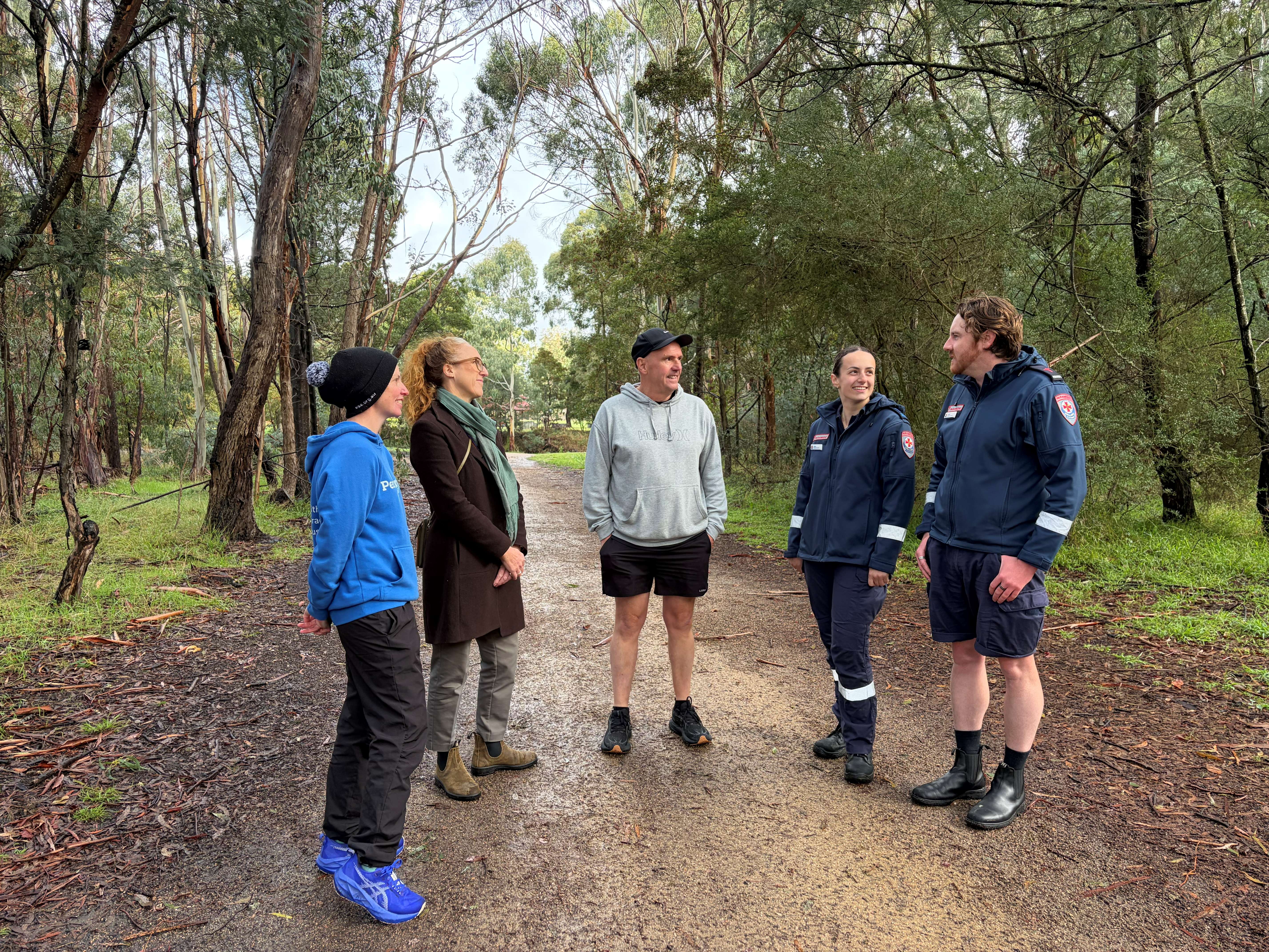 Five people including two paramedics chat on a trail.