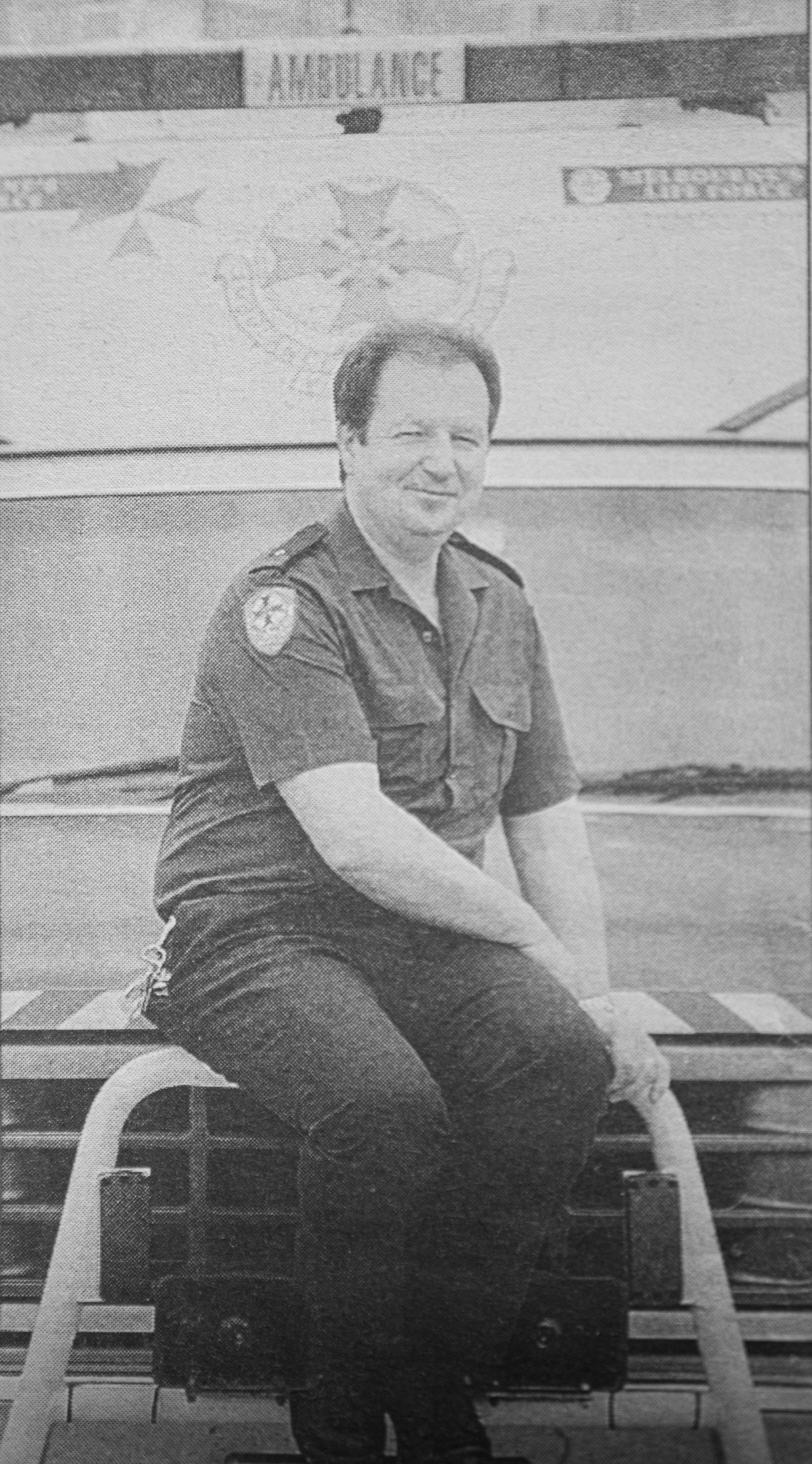 A black and white photo of a paramedic and a now vintage ambulance.