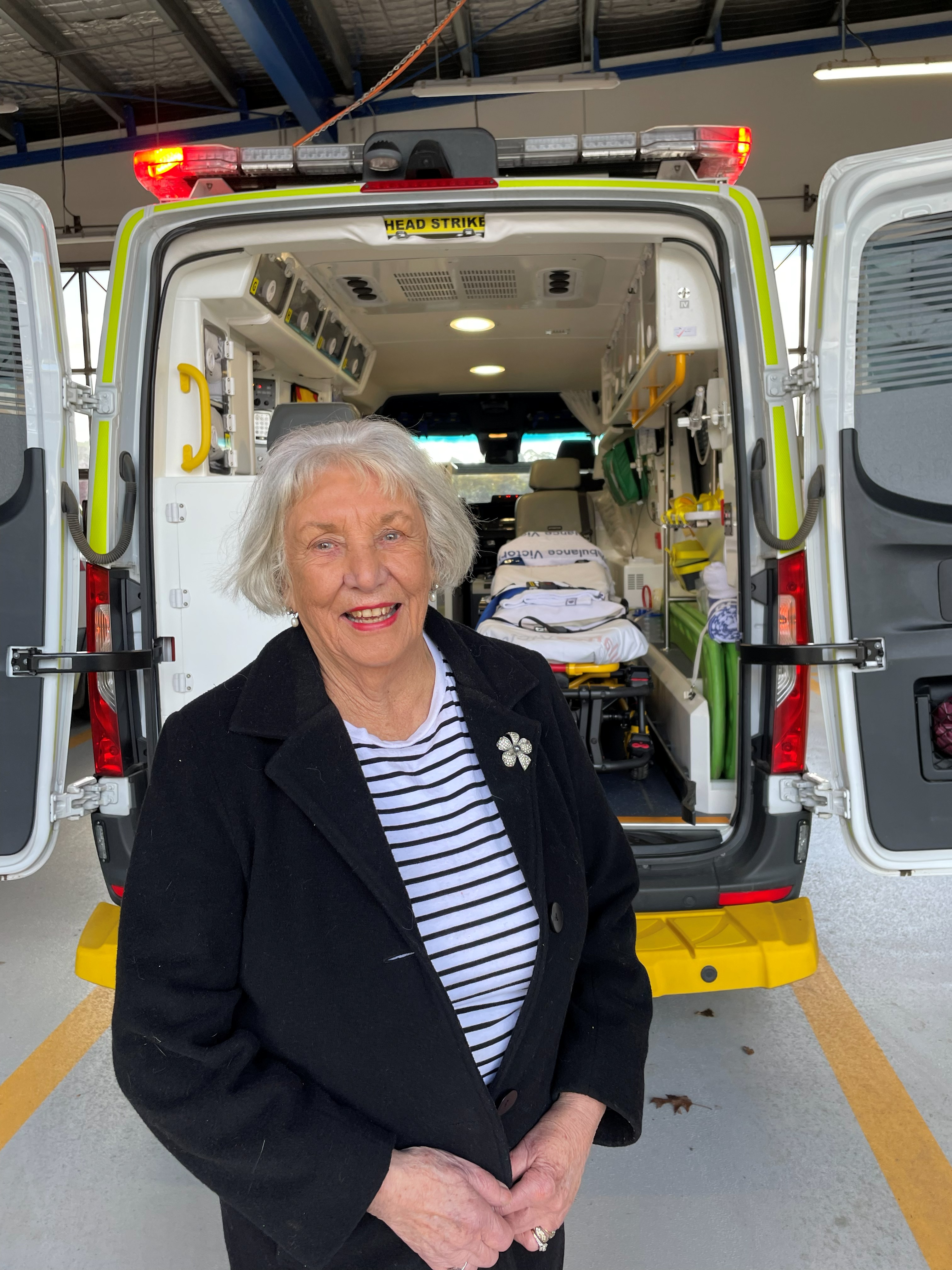 A woman smiles at the back of an ambulance.