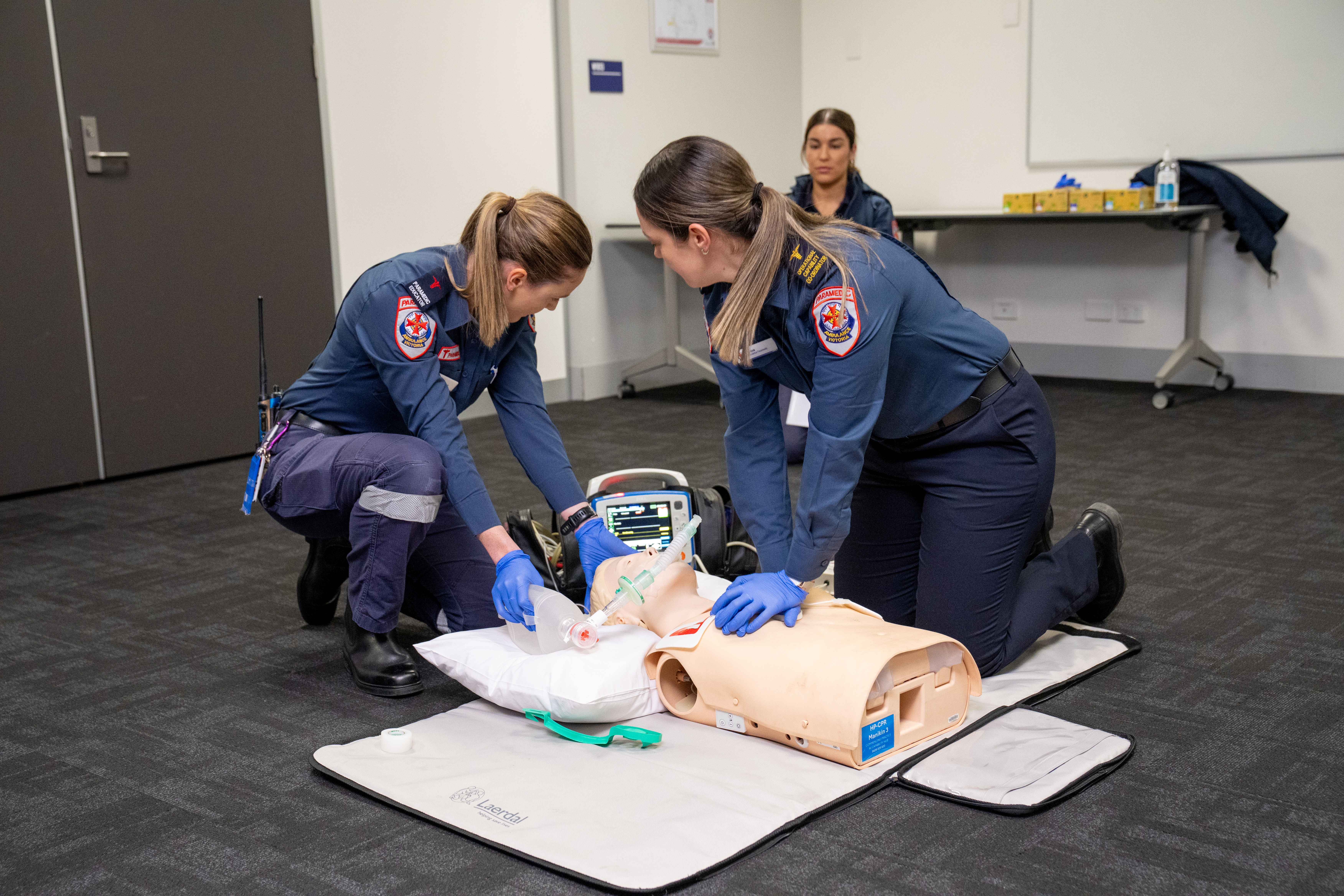 Two female graduate paramedics performing CPR on a training manikin. 