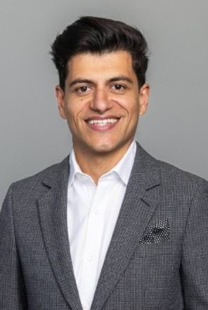 A man in business clothes smiles at the camera