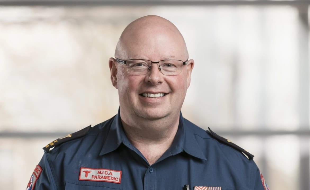 A man in MICA paramedic uniform stands for a posed photo