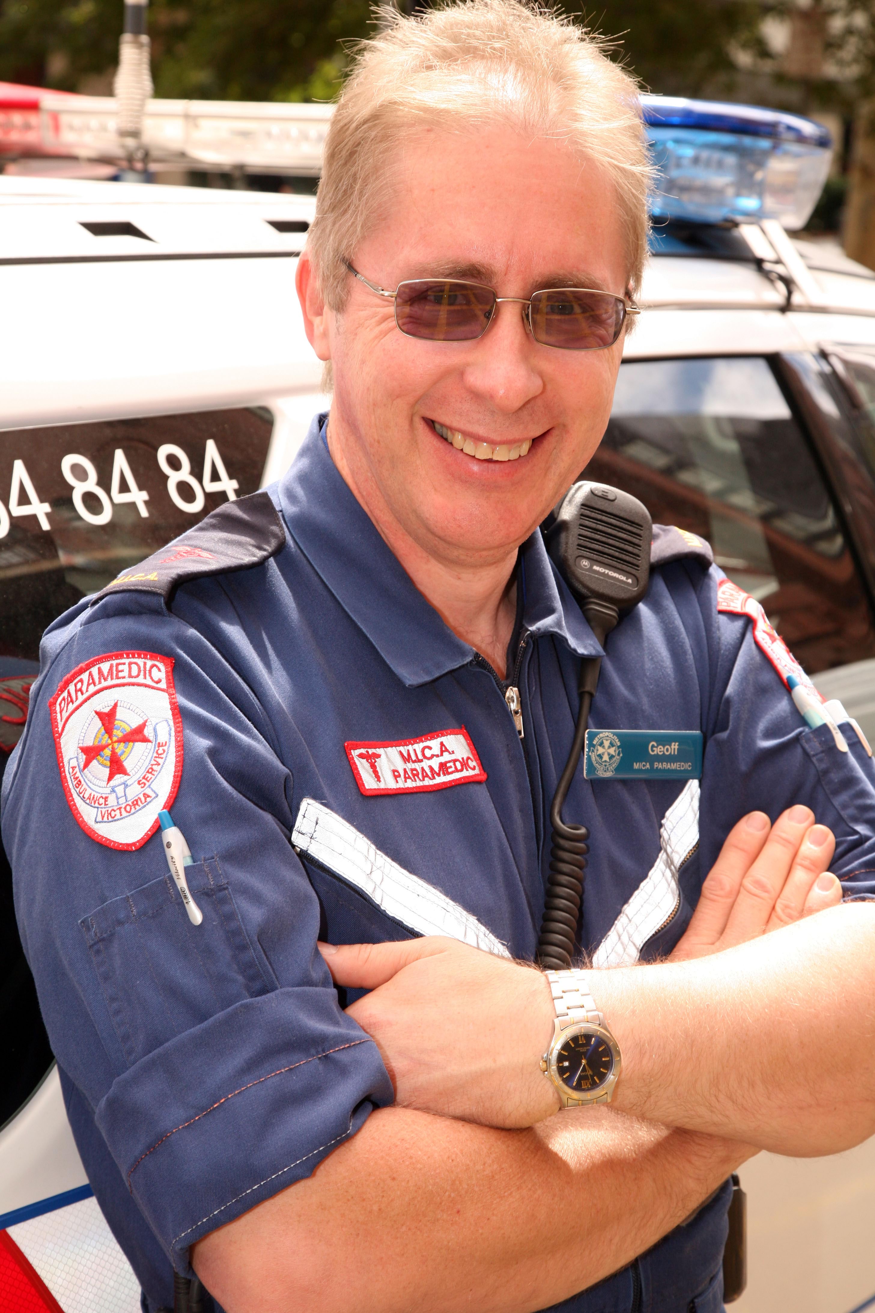 A MICA paramedic smiles in front of an ambulance vehicle.