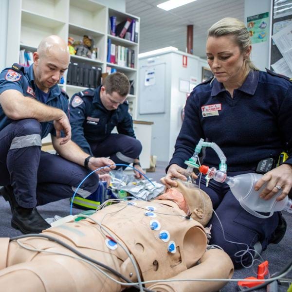 Three paramedics train on a mannequin