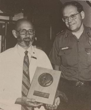 An aged photo of two men. The man on the right is wearing a paramedic uniform.