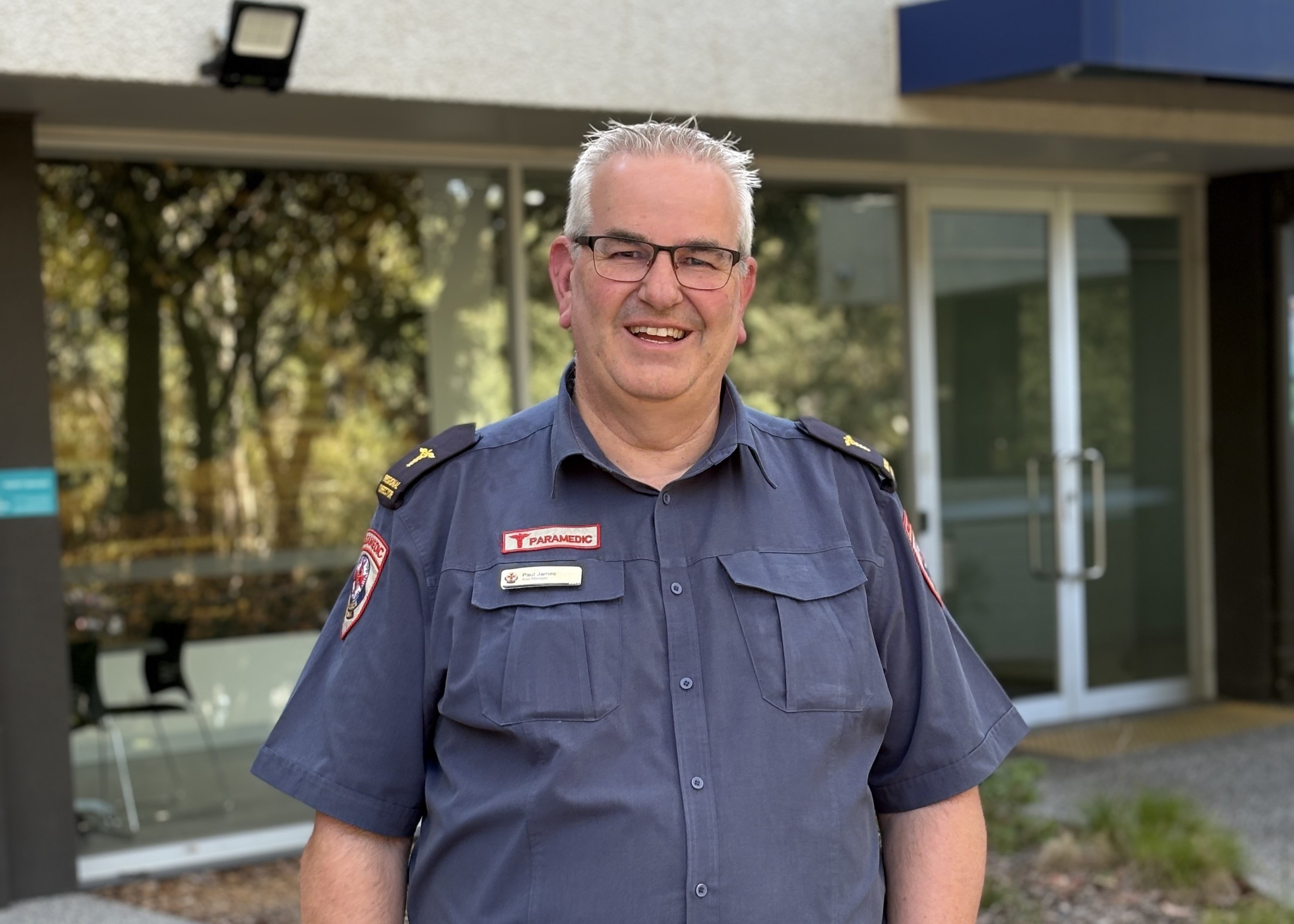 A man in Ambulance Victoria paramedic uniform smiles for the camera.