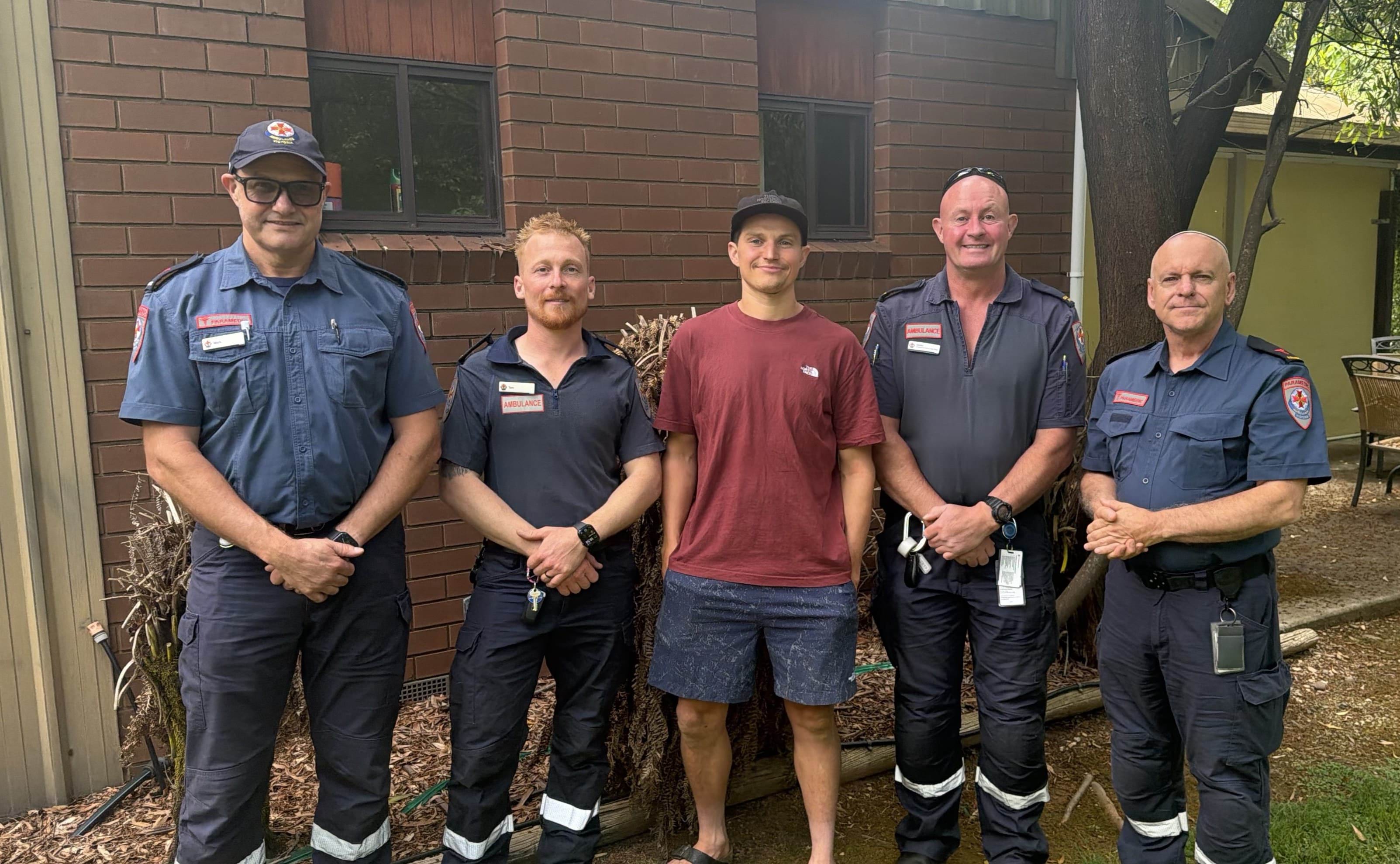 A man smiles alongside four people in Ambulance Victoria uniform.