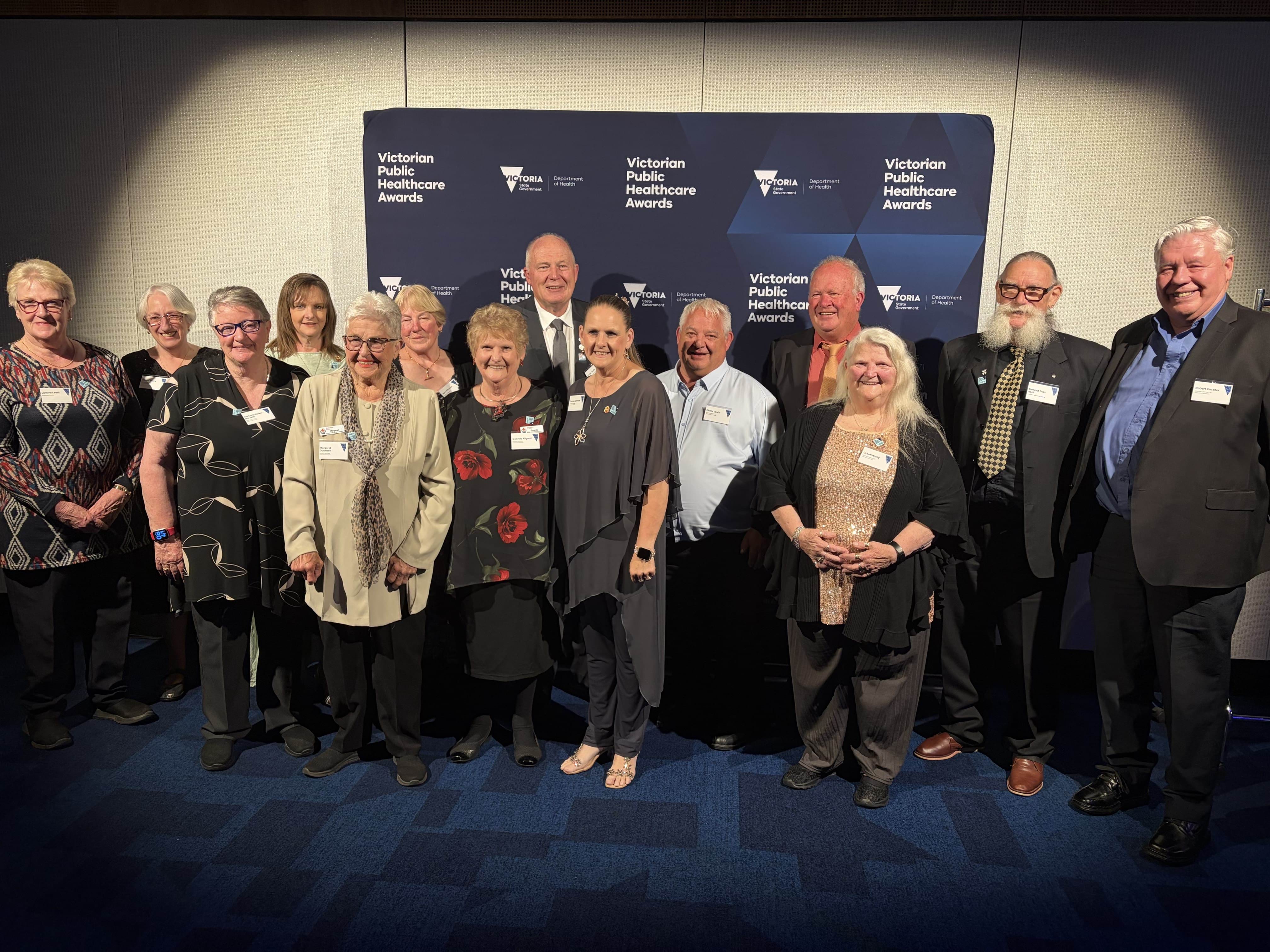 A group of 14 people smiling at the camera.