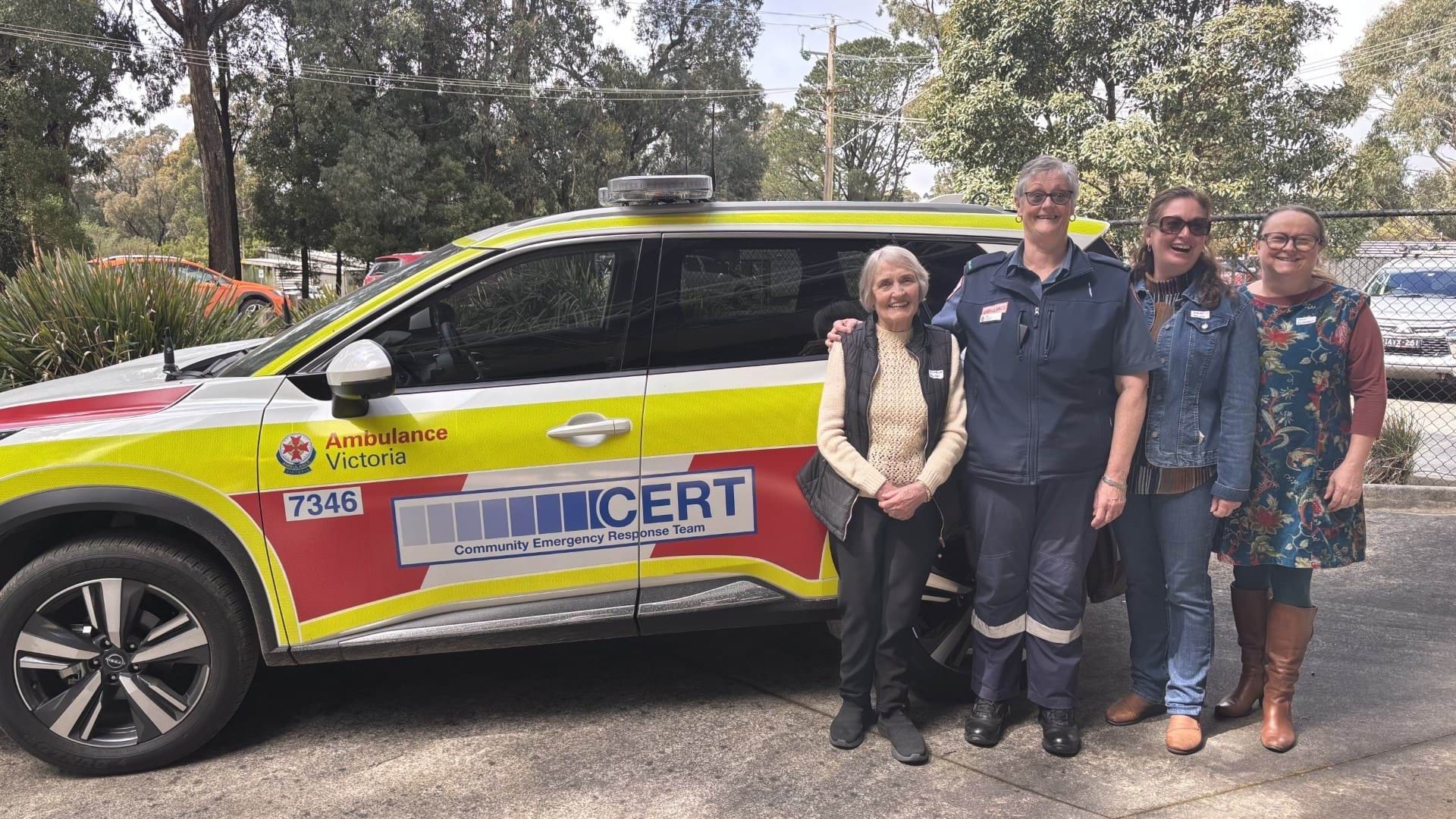Four people stand in front of an Ambulance Victoria CERT team car.