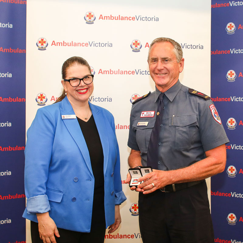 Ambulance Victoria CEO and paramedic Dale Richards stand in front of branded background