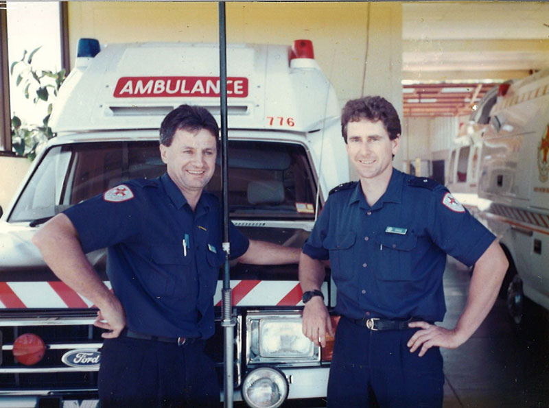 Two Ambulance Victoria paramedics stand in front of ambulances